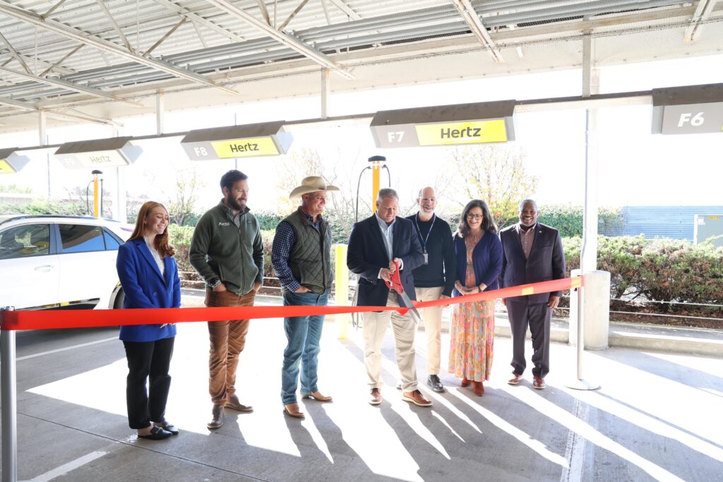 people gather around ribbon cutting